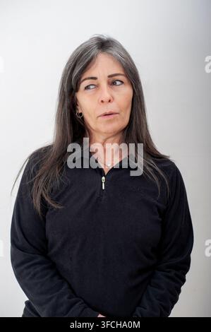 Portrait d'une femme d'âge moyen aux cheveux gris regardant de côté avec une expression pensive. Photo de studio sur fond neutre avec une lumière naturelle douce. Banque D'Images