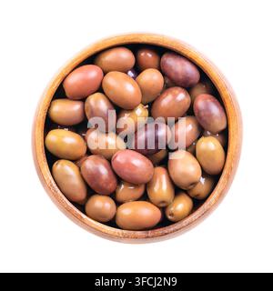 Olives Nostraline, olives noires avec pépins dans un bol en bois, isolées par-dessus. Olives de table italiennes entières, de forme effilée et de couleur pourpre. Banque D'Images