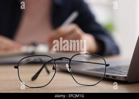 Mots-clés. Verres sur la table et femme écrivant dans un carnet, mise au point sélective Banque D'Images