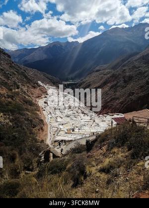 Vue panoramique des mines de sel de Maras à Cusco, au Pérou. Anciens bassins d'évaporation de sel dans la Vallée Sacrée sous des nuages dramatiques et des rayons de soleil. Banque D'Images