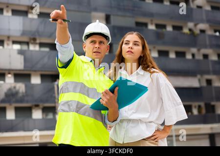 Ingénieur parlant avec la femme sur le chantier de construction Banque D'Images