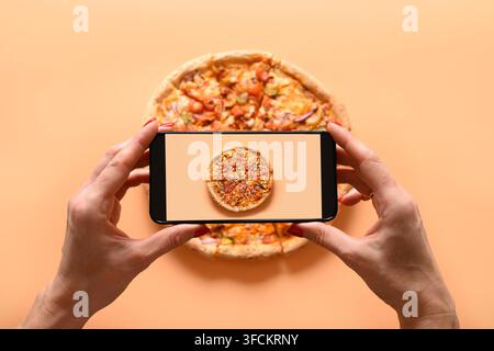 Femme mains prend la photographie de pizza végétalienne italienne avec tomate, mozzarella, sauce. Vue de dessus. Photo de smartphone pour les réseaux sociaux. Banque D'Images