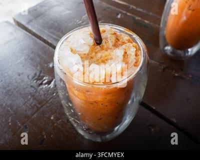 Thé au lait thaïlandais glacé mélangé au café servi dans une tasse à double paroi Banque D'Images