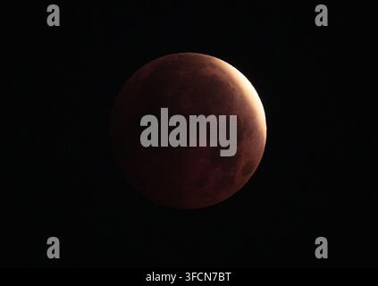 L'éclipse partielle lunaire du plein mois d'août, connu sous le nom de Lune des Esturgeons, est visible dans le ciel au-dessus de l'Isle of Dogs, à Londres. Date de la photo : vendredi 28 août 2026. Banque D'Images