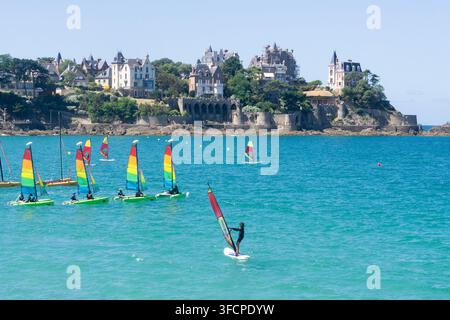 Catamarans et windsurfeurs dans la baie en contrebas des villas de la Belle Époque de Dinard, Ille-et-Vilaine, Bretagne, France. Banque D'Images