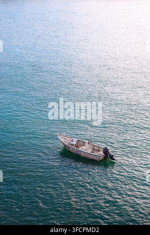 Petit bateau à moteur vide flottant sur l'eau calme Banque D'Images