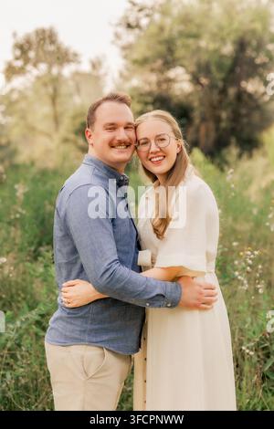 Jeune couple souriant qui s'embrasse en plein air dans un champ ensoleillé Banque D'Images