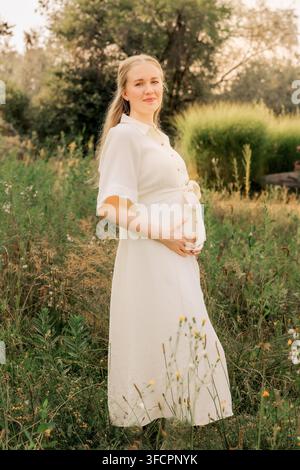 Femme enceinte heureuse souriant dans un magnifique pré estival Banque D'Images
