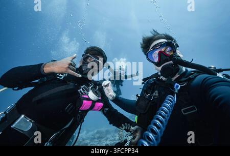 Trois plongeurs posant pour un selfie amusant sous l'eau Banque D'Images