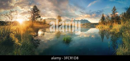 Paysage lacustre panoramique pittoresque en Allemagne au lever du soleil avec des montagnes, des arbres, un ciel coloré magnifique, une belle lumière matinale et des reflets clairs dans l Banque D'Images