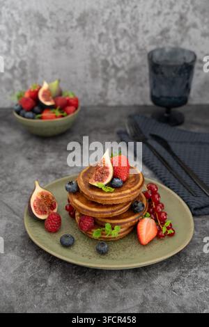 Scène de petit-déjeuner stylisée mettant en vedette des crêpes moelleuses garnies de figues, de fraises et de fruits de saison Banque D'Images