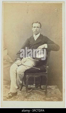 Un homme, vêtu d'une tenue formelle, est assis sur une chaise avec un chapeau à la main et une canne à côté de lui, dans un portrait photographique du XIXe siècle par Alophe, un photographe français. Banque D'Images