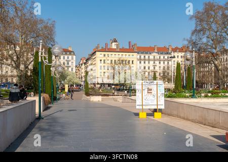 Lyon, France - 08 mars 2026 : Une journée ensoleillée à Lyon, en France, met en valeur les arbres en fleurs et les bâtiments européens classiques le long d'une large avenue Banque D'Images