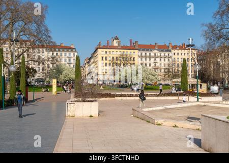 Lyon, France - 08 mars 2026 : Une journée ensoleillée à Lyon, en France, met en valeur les arbres en fleurs et les bâtiments européens classiques le long d'une large avenue Banque D'Images