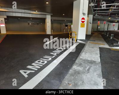 Espace de stationnement intérieur ou allée avec "Ambulance uniquement" peint en blanc sur la surface sombre en asphalte à côté d'une flèche directionnelle. Singapour Banque D'Images
