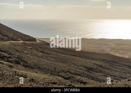 Vue du paysage volcanique accidenté et de la route de terre sinueuse menant vers l'océan Atlantique à Cofete, îles Canaries, Espagne Banque D'Images