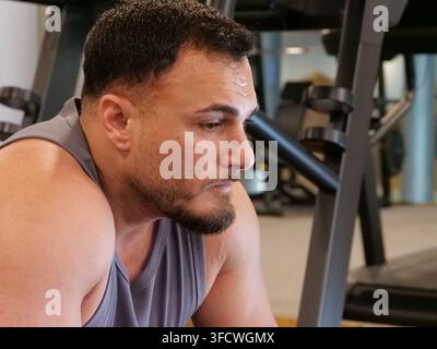 Gros plan du profil latéral d'un homme musclé concentré avec de la sueur sur le front, se reposant après un entraînement intense à la salle de sport. Concept de dévouement, d'épuisement Banque D'Images