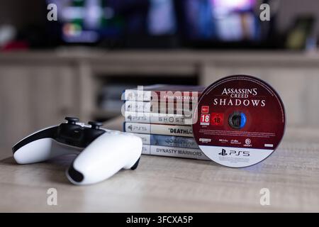 BRECHT, BELGIQUE – 28 août 2026 : Portrait d'une pile de jeux PlayStation PS5 avec un disque de jeu debout contre elle et une manette posée à côté Banque D'Images