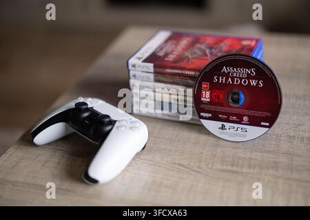 BRECHT, BELGIQUE – 28 août 2026 : Portrait macro d'une pile de jeux PlayStation PS5 avec un disque de jeu dressé contre elle et une manette posée à côté Banque D'Images