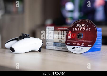 BRECHT, BELGIQUE – 28 août 2026 : Portrait rapproché d'une pile de jeux PS5 PlayStation avec un disque de jeu dressé contre elle et une manette posée à côté Banque D'Images