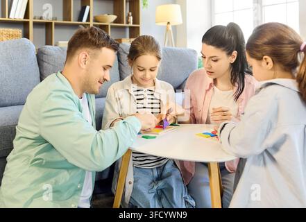 Famille joyeuse avec parents et enfants jouant ensemble à un jeu de société à la maison Banque D'Images