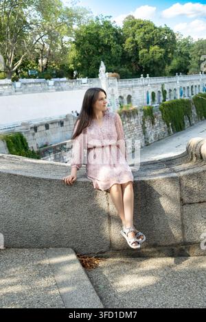 Belle femme brune adulte assise en plein air dans un parc urbain. Banque D'Images