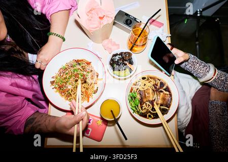 Femmes asiatiques mangeant de la nourriture asiatique dans un café et utilisant un smartphone Banque D'Images