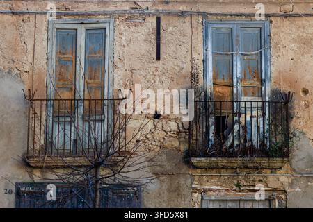 Deux balcons rustiques et usés avec des rampes en fer rouillé sur une façade de bâtiment méditerranéen abandonné. Banque D'Images