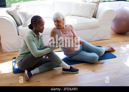 Sénior et entraîneur afro-américain en vêtements de sport utilisant une tablette sur des tapis de yoga avec une balle rose Banque D'Images