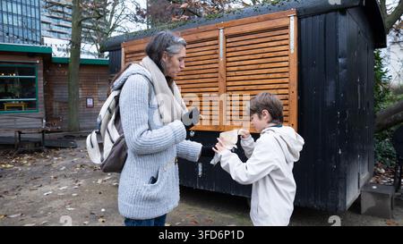 Femme et garçon savourant de la nourriture d'un vendeur de rue dans un cadre urbain en plein air Banque D'Images