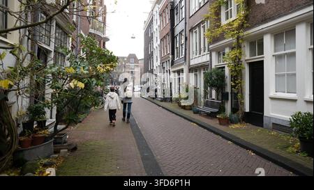 Femme et garçon marchant le long d'une rue pavée bordée de maisons de canal hollandaises Banque D'Images