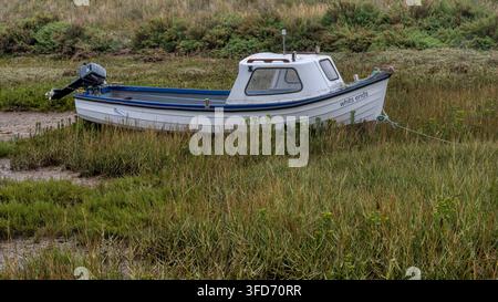 Petit bateau posé sur la boue à marée basse à côté du port de Burnham Overy Staithe, Norfolk, Royaume-Uni Banque D'Images
