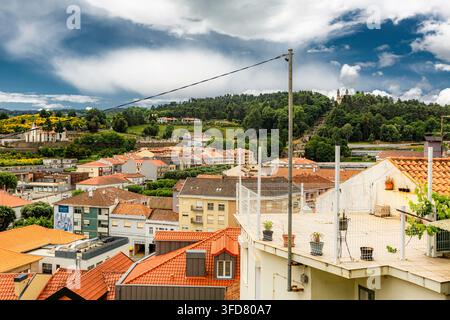 Lamego Portugal, vue panoramique de la ville de Lamego, au Portugal, montrant des toits en terre cuite. Des collines couvertes d'arbres verts entourent le village. Le ciel est dramatique Banque D'Images