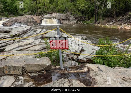 Un panneau "Danger Do Not Cross" se dresse derrière une barrière à chaîne au-dessus d'une cascade rocheuse à l'Upper Falls Overlook, Linville Falls, Caroline du Nord, États-Unis Banque D'Images