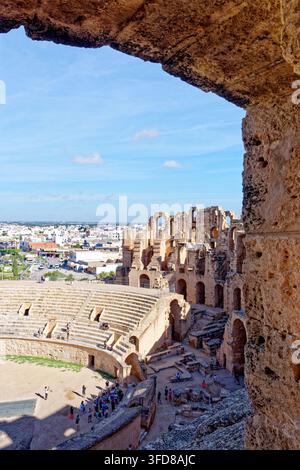 Une perspective verticale à angle élevé regardant à travers une arche ancienne en pierre vers le sol de l'arène, les gradins et les murs dramatiquement en ruines d'El Jem A Banque D'Images