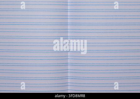 Texture de carnet à papier ligné montrant un pli central et une agrafe métallique Banque D'Images