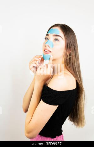 Portrait de beauté en profil latéral élégant mettant en avant des patches sous les yeux bleus pour l'hydratation et le soin de la peau. Composition minimale isolée avec espace de copie. Banque D'Images