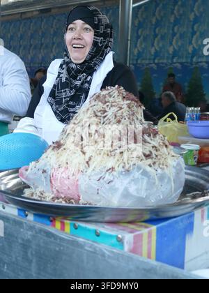 TACHKENT - 20 SEPT 2024 - Femme portant un hijab travaillant comme vendeuse de nourriture, vendant de la glace rasée traditionnelle avec des garnitures sur un étal de marché en plein air à Tachkent Banque D'Images