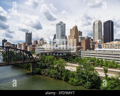 Pittsburgh Pennsylvanie-06 21 2026 : Vue en hauteur d'une ligne d'horizon urbaine encadrant des tours de bureaux proéminentes derrière des infrastructures fluviales et des arbres. Banque D'Images