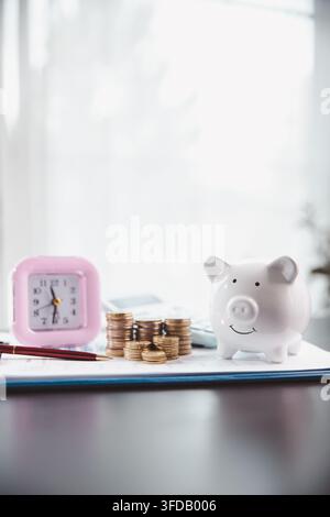 Une horloge rose, un cochon de banque blanc, des pièces empilées, une calculatrice et une feuille de planification illustrent les économies basées sur le temps, la budgétisation domestique, la discipline financière Banque D'Images