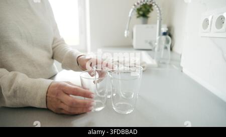 Femme pose des verres lavés sur la table avec gros plan sur la main Banque D'Images