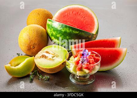 Melons variés et pastèque servis comme une sélection de fruits d'été frais, avec des fruits coupés et des morceaux de melon dans un bol en verre. Banque D'Images