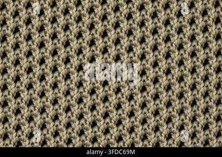 Tissu de laine beige présentant une texture tricotée détaillée avec un motif de maille ouverte répétitif Banque D'Images