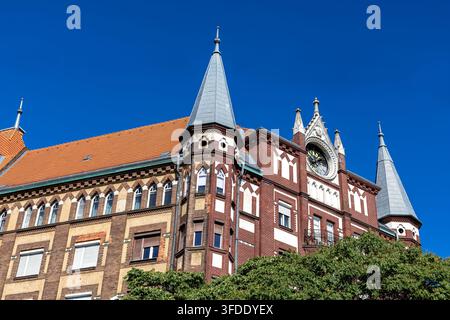 Bâtiment historique en briques avec horloge à Budapest, Hongrie. Bâtiment historique en briques avec des flèches ornées et une horloge sous un ciel bleu clair à Budapest Banque D'Images