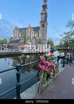 Un vélo, enchaîné à la rambarde du canal Prinsengracht, est décoré de fleurs près de la Westerkerk dans le quartier Jordaan d'Amsterdam Banque D'Images