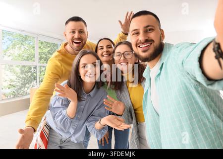 Diversité et inclusion, une équipe joyeuse et diversifiée de jeunes professionnels prenant un selfie ensemble dans un environnement de bureau moderne et lumineux Banque D'Images