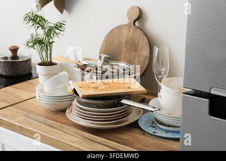 Ménages et épuisement domestique, pile de vaisselle sale et comptoir de cuisine en désordre après un dîner avec des ustensiles de cuisine non lavés et des résidus de nourriture Banque D'Images