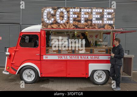 Camion café Citroën H rouge devant le stade de Liverpool FC avec une enseigne illuminée, un barista servant des boissons et le slogan You'll Never Walk Alone. Banque D'Images