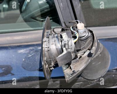 Gros plan extrême détaillé d'un rétroviseur de voiture brisé. La couverture extérieure en plastique est complètement cassée, exposant des fils électriques colorés, interna Banque D'Images