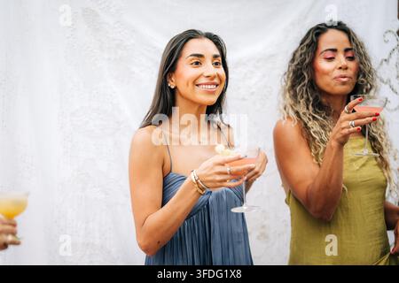 Des femmes heureuses buvant des cocktails colorés lors d'une fête Banque D'Images